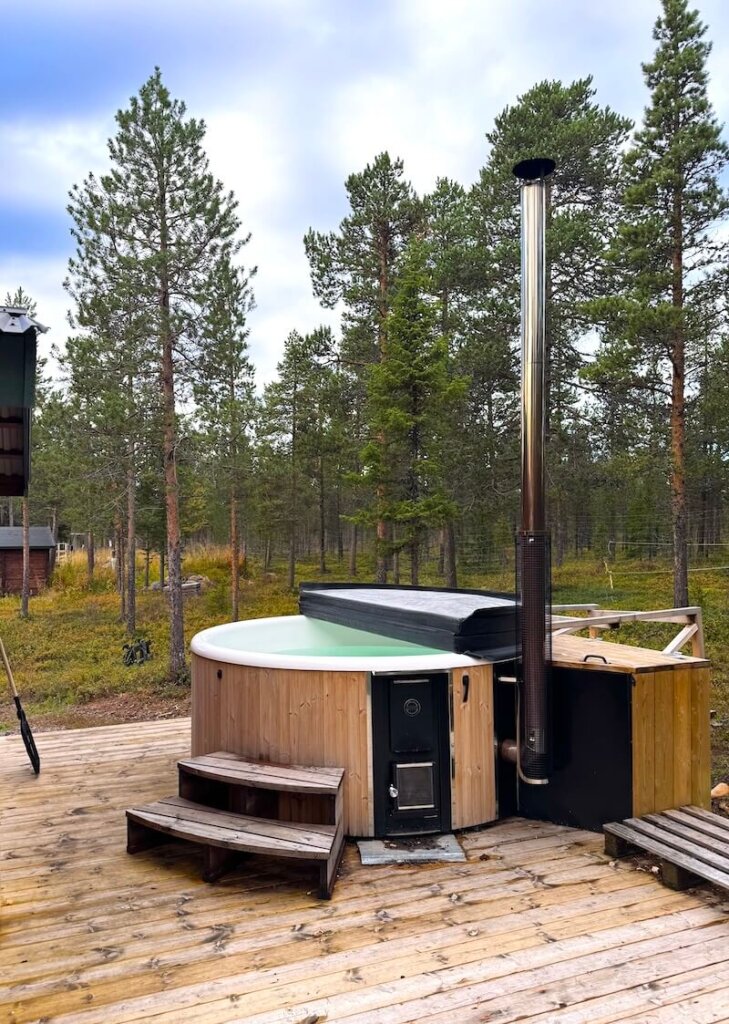 Wood-fire hot tub outside with the pipe for the wood stove during the day time