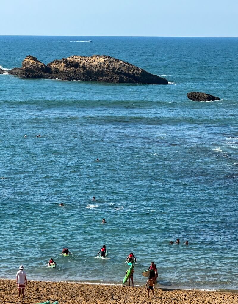 Surfers coming in from the waves after an afternoon surf lesson with lots of people still out enjoying the water
