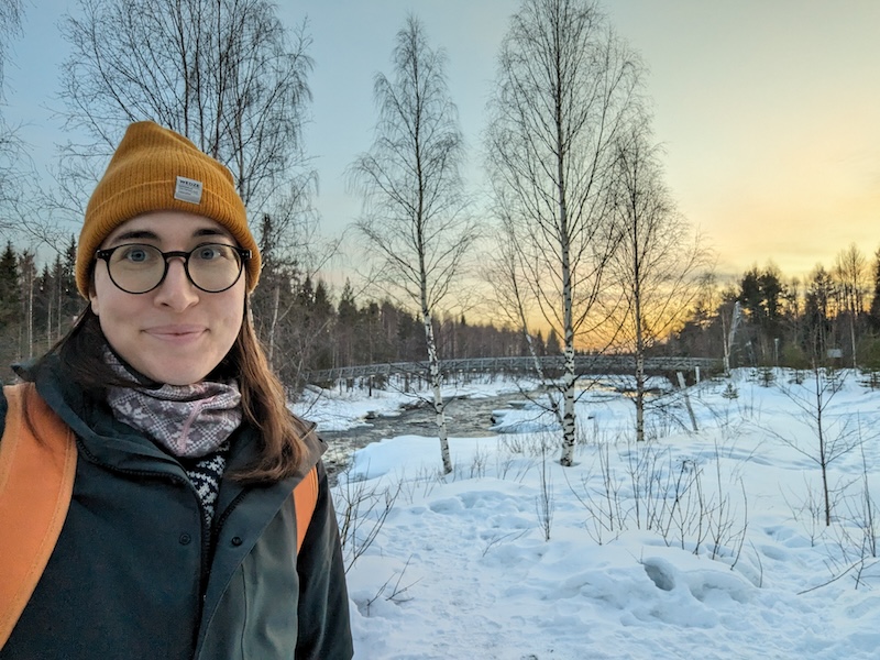 Allison Green wearing a hat, scarf, and parka and orange backpack in the winter month of March