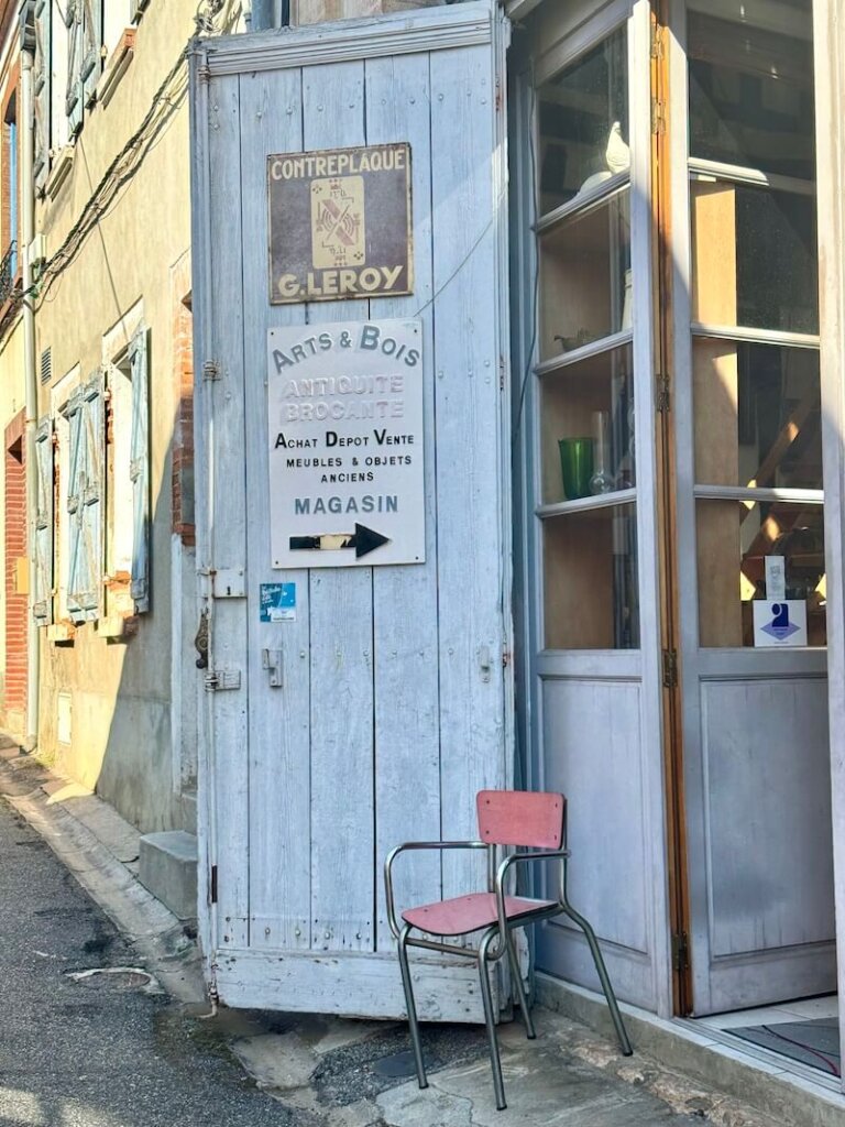 The entrance to an antique shop (brocante) with a pale blue door in Samatan