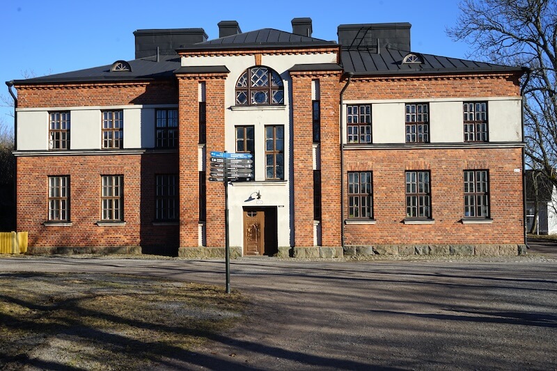 Signpost orienting you to different points of interest and a historic building behind it