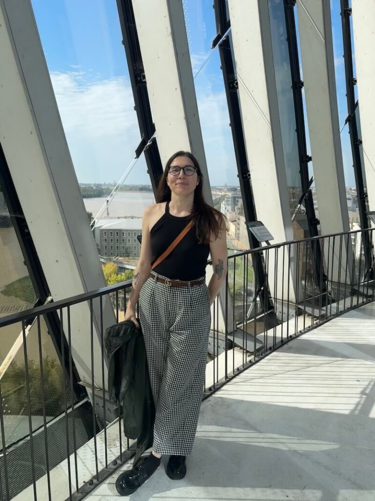 Allison Green, the author of the article, wearing fall clothes and smiling posing with a view of Bordeaux behind her