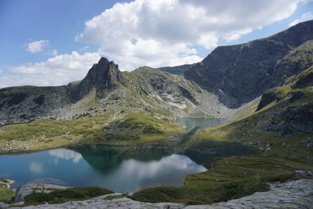 A mountain in the Rila Lakes with dark blue water, glassy, reflecting back the clouds from the day