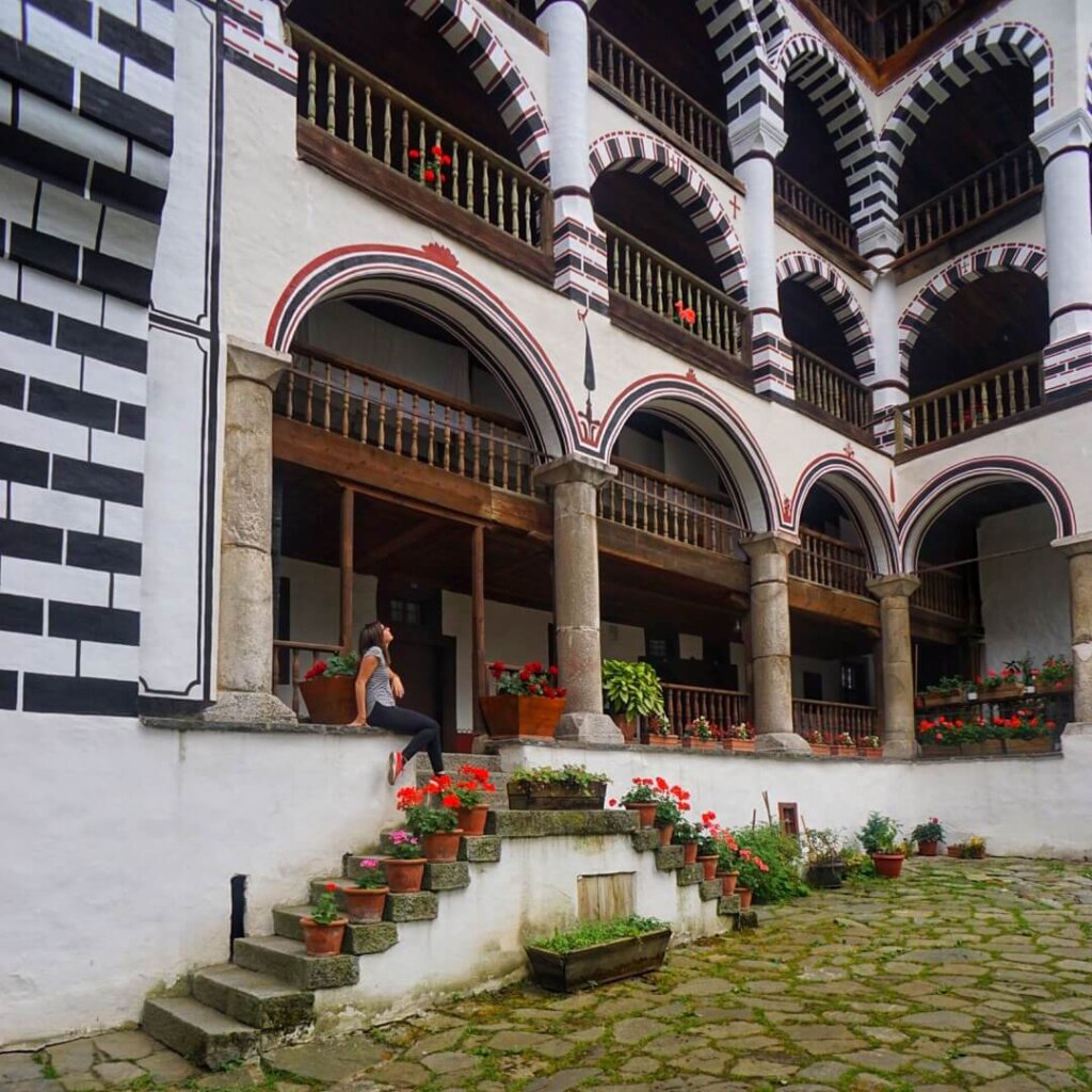 Allison Green sitting on the stairs to the upper levels of the monastery