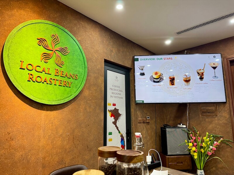 Local Beans Roastery sign with a TV showing a powerpoint of different coffee types you try on the tour