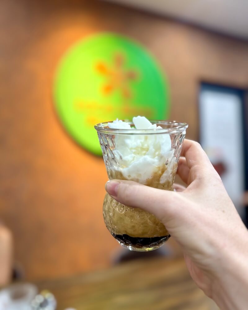 Allison's hand holding the icy slushy of coconut cream and coffee that is popular in southern vietnam