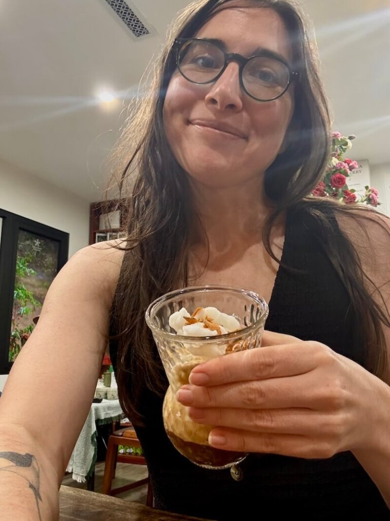 Allison Green the author of the article smiling and holding her coconut iced coffee