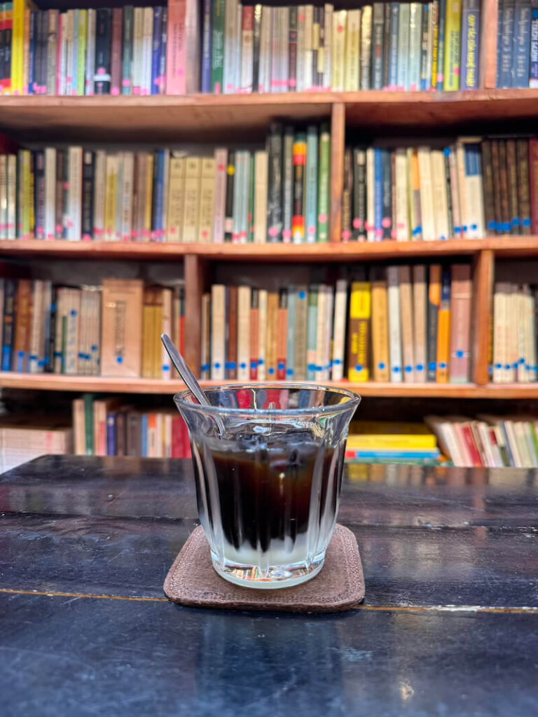 Black coffee with condensed milk at the bottom, with books around