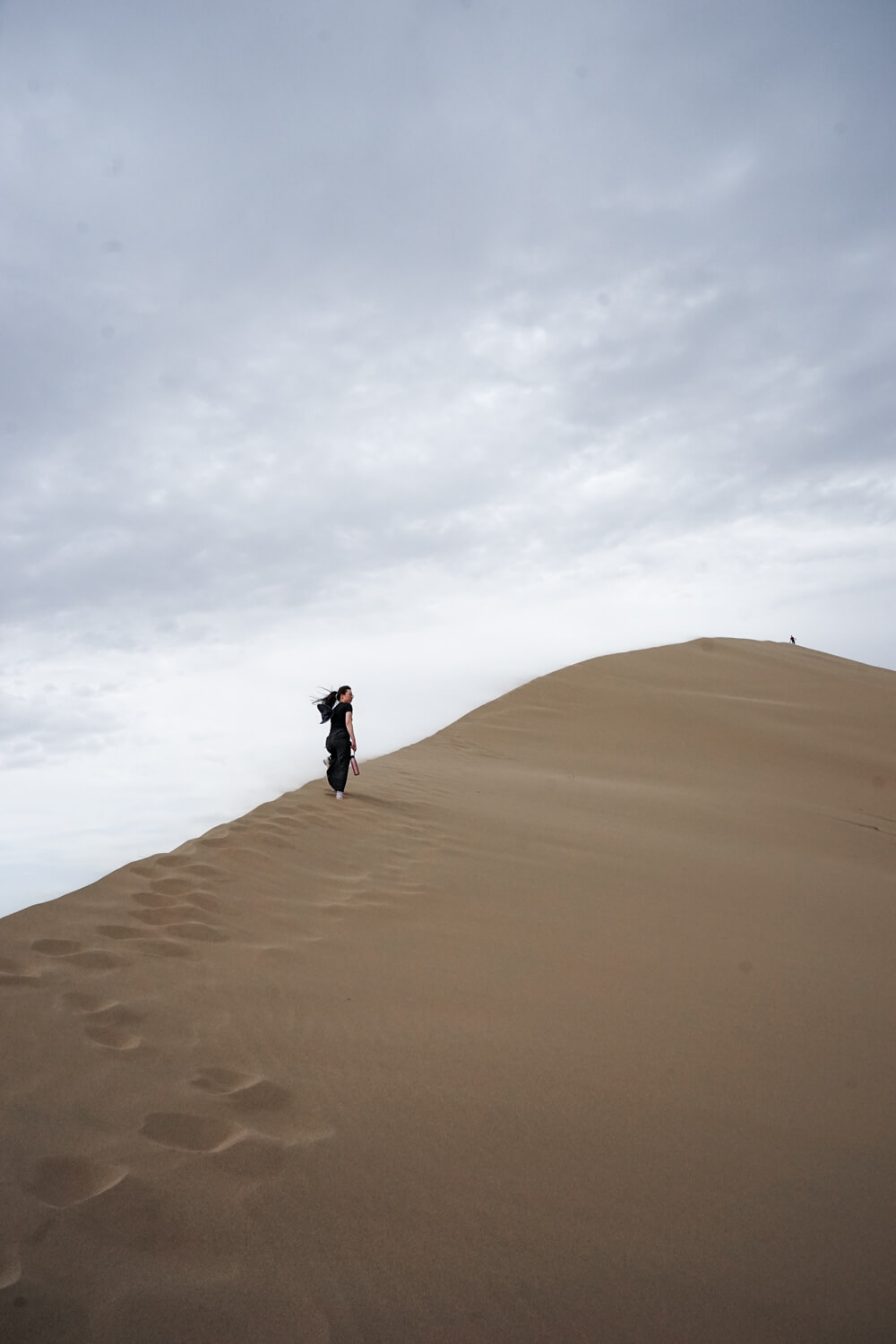 Woman climbing up the very steep dune