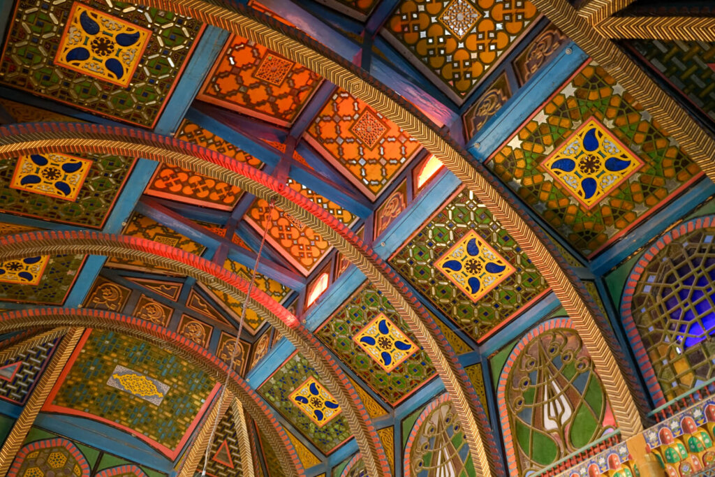 Detail of the ceiling with colorful stained glass panels adding an interesting lighting pattern to the ceiling paintings