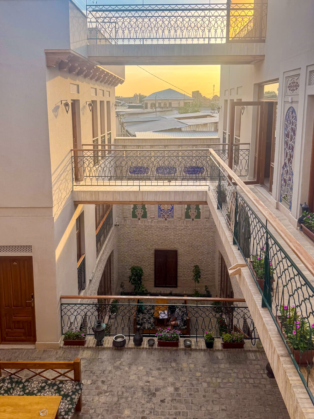 Sunset hour at Bukhara's Duston Hotel with the view of the sun setting in the distance and the multiple levels of the historic home