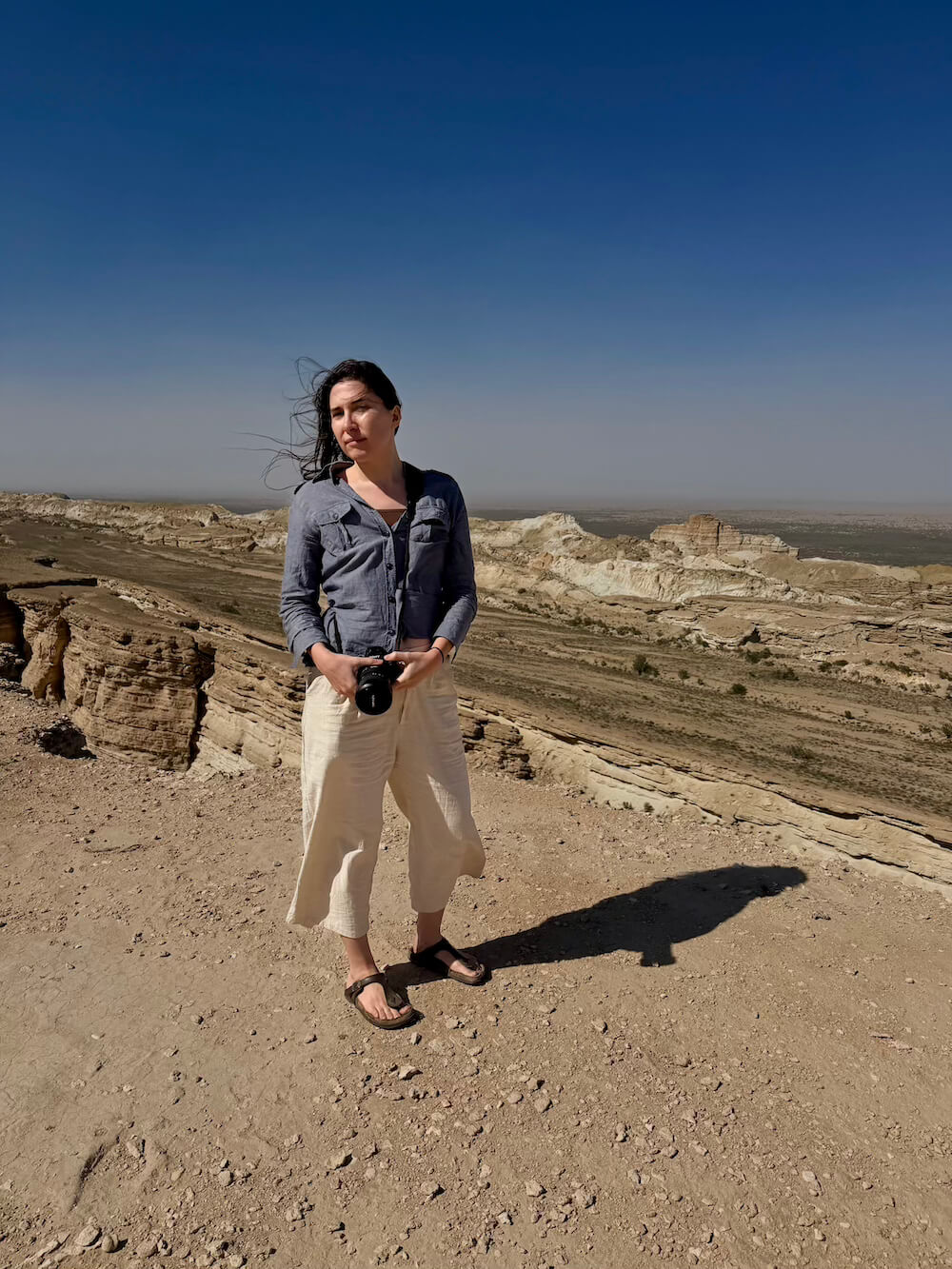 Allison wearing a button up over a brown shirt and linen pants in the desert in Karakalpakstan autonomous republic