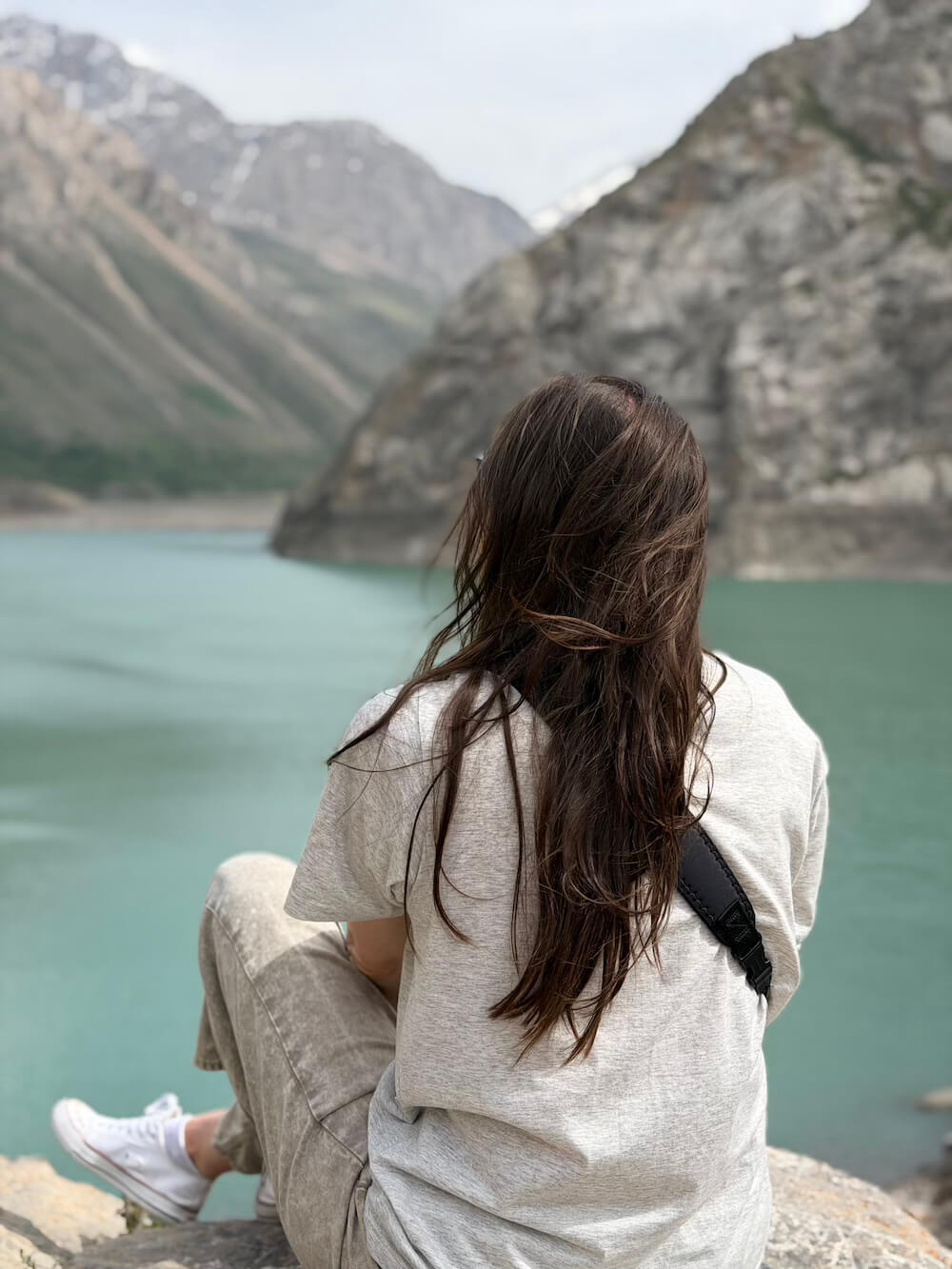 Allison sitting with her back to the camera wearing gray pants and gray jeans and converses