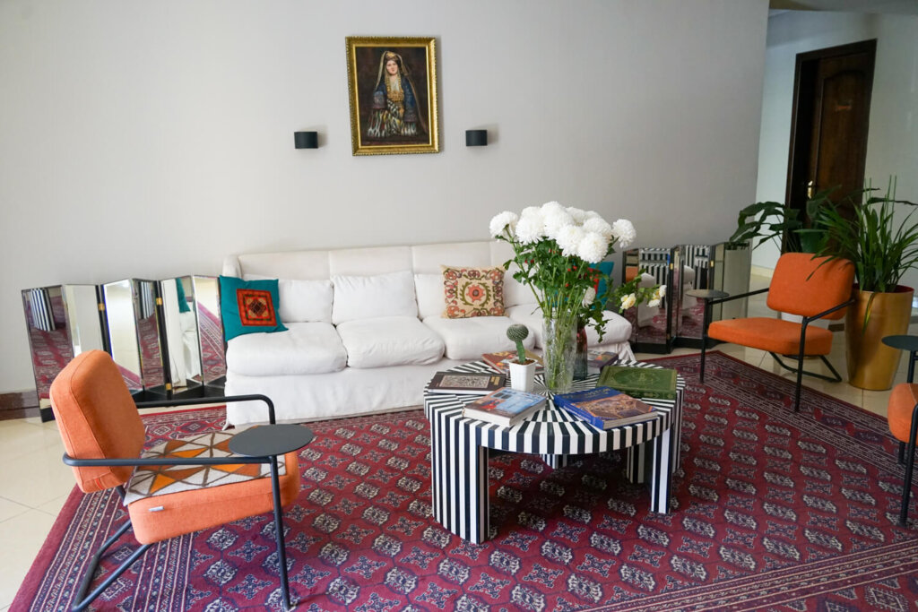 Interior of the Jipek Joli lobby, with a white sofa, orange chairs, and striped coffee table
