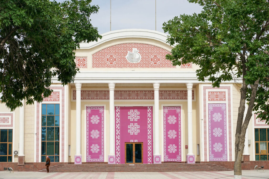 Pink and red building facade with pillars and a motif like embroidery