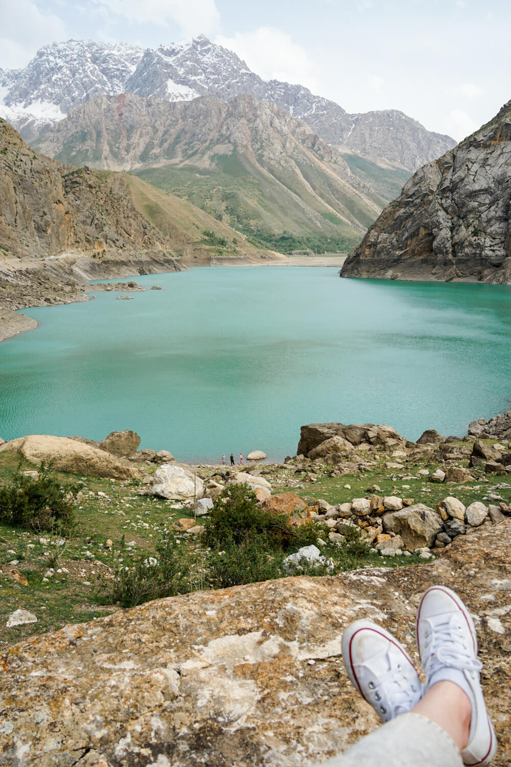 Allison's feet in shoes at the foot of the sixth lake in the seven lakes of tajikistan