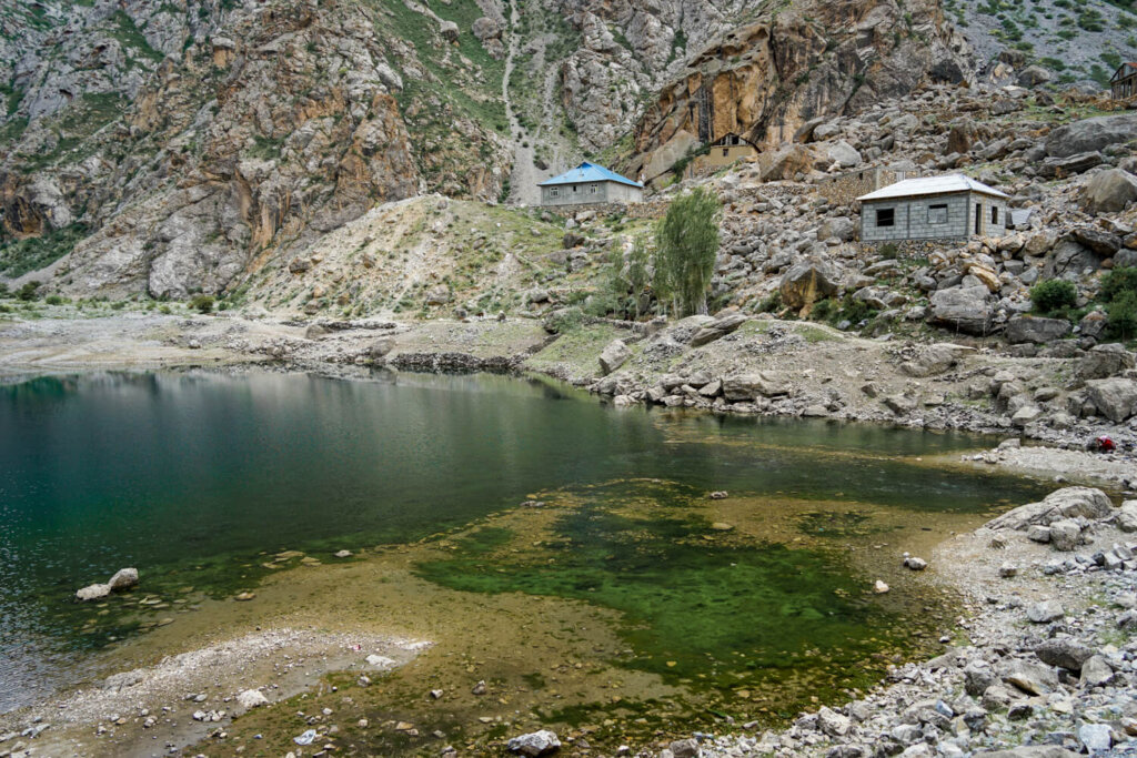Shallow lake with green, turquoise shades next to a village. Small lake with very little water in it.